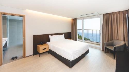 a bedroom with a bed and a chair and a window at PANAQ operated by SONO in Yeongdeok