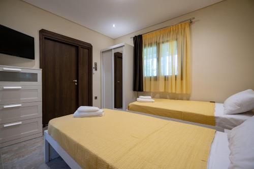 a hotel room with two beds and a television at Seaside Serenity Retreat - Nea Makri by ΜΡS in Nea Makri