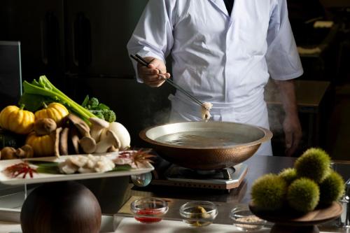 a chef is mixing vegetables in a wok at Kobe Suma Seaworld Hotel in Kobe