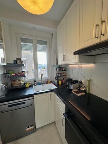 une cuisine avec des armoires blanches et un comptoir noir dans l'établissement Your home at the Luxembourg garden, à Paris