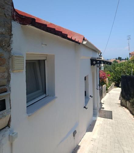 a white house with a window on a street at Kantouni Mezzamorto in Lefkímmi