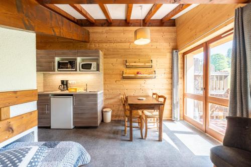 une cuisine et une salle à manger avec une table dans une cabine dans l'établissement Studio 16 - Le Lagopede, à Cohennoz