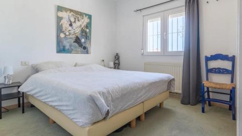 コンブレ・デル・ソルにあるLarge villa, great view with private swimming poolのベッドルーム1室(ベッド1台、青い椅子付)