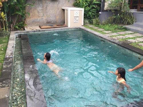 two children swimming in a swimming pool at Ratna Villa in Ubud