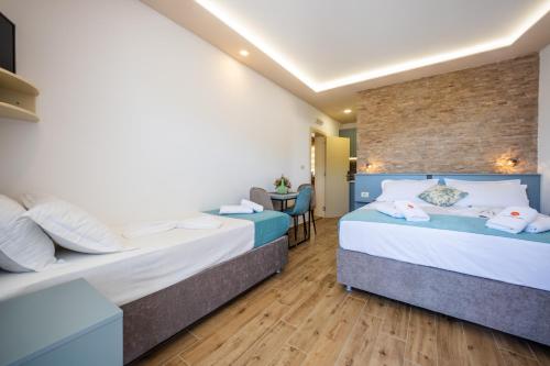 two beds in a hotel room with wooden floors at Guest House S-Lux in Petrovac na Moru