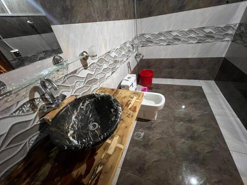 a bathroom with a black sink and a toilet at Relax Cottages & Resort Kalam in Kalām
