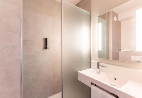 Un baño con ducha, lavabo y espejo. en B&B HOTEL Cholet Nord, en Cholet