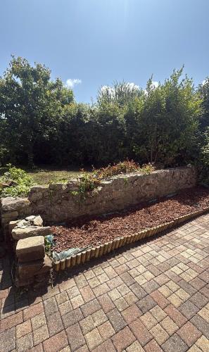 a garden with a stone wall and some bushes at Maison de vacances Audierne centre avec terrasse proche des plages in Audierne