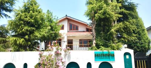 a house behind a white fence with trees at Greenoriva - D2 - Greenery & Peace in Srinagar