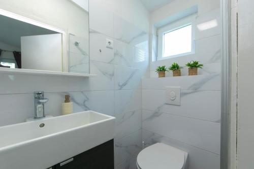 a white bathroom with a sink and a toilet at Apartmani Drašnice 2 in Drašnice