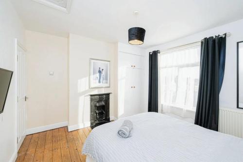 a white bedroom with a bed and a fireplace at 4 Bedroom House For Corporate Stays in Kettering in Kettering