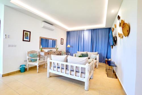 a living room with white furniture and blue curtains at Diani Beachfront Villa Amani at Diani in Ukunda