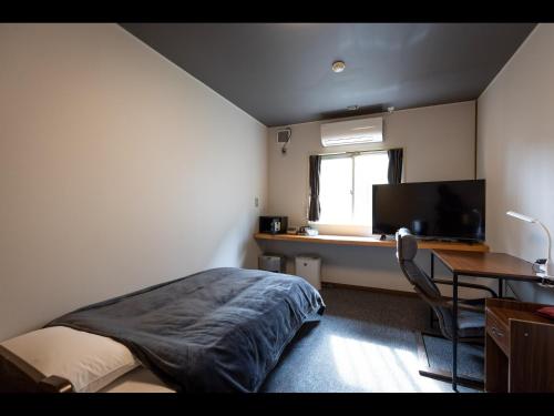 a bedroom with a bed and a desk and a television at Kiso Mikawaya in Kiso