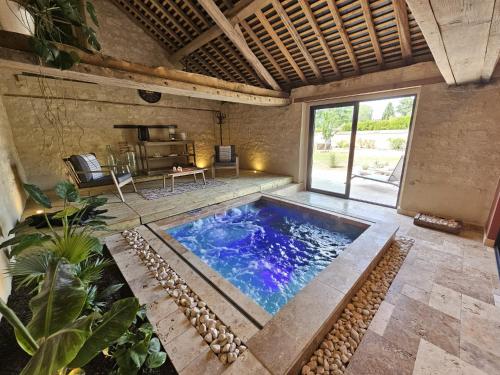 une grande piscine intérieure dans une pièce avec une table dans l'établissement Le Clos des Oliviers, à Bourgueil