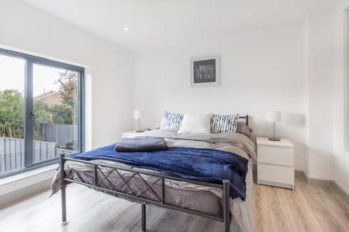 a bed in a white room with a large window at Zest Homes 87b Bridge Street in Leominster