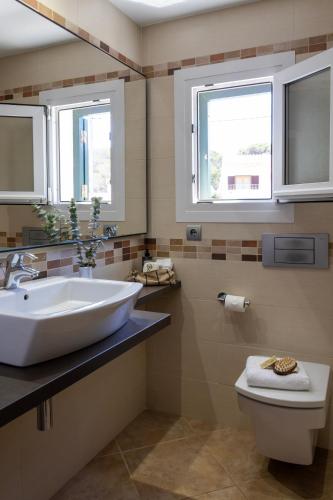 a bathroom with a sink and a toilet and two windows at Menurka - Cala Blanca in Cala Blanca
