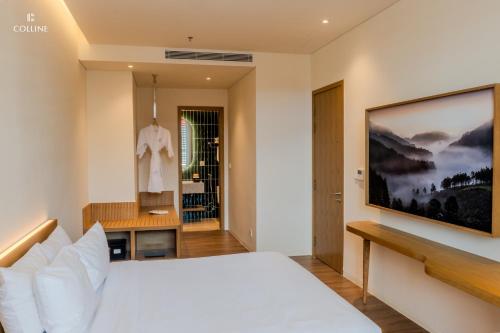 a bedroom with a white bed and a television on the wall at Colline Dalat in Da Lat