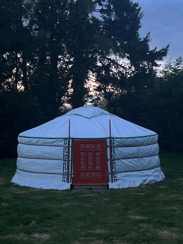 une grande yourte avec une porte rouge dans un champ dans l'établissement Yourte Mongole En Normandie, 