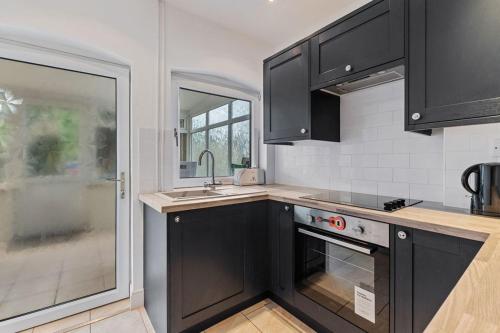 a kitchen with black cabinets and a sink at 4 bedroom house near Burton Latimer, Wellingborough and Isham in Isham