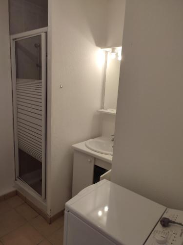 une salle de bain blanche avec un lavabo et une douche dans l'établissement Appartement T2 avec balcon, centre de Castelnau de Médoc, à Castelnau-de-Médoc