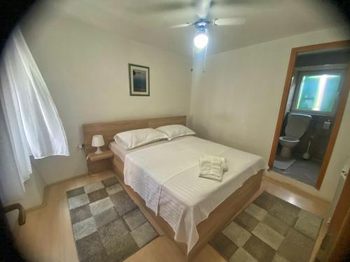 a small bedroom with a white bed and a window at Apartman Roko in Tribunj