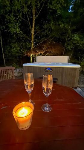 two wine glasses and a candle on a table at Bluebell Cottage - with hottub in Newry
