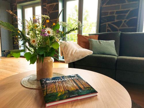 a vase of flowers on a table with a book at Ferienhaus NaturReich in Bad Berleburg