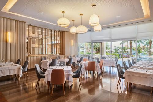 a restaurant with white tables and chairs and large windows at Hipotels Playa de Palma Palace&Spa in Playa de Palma