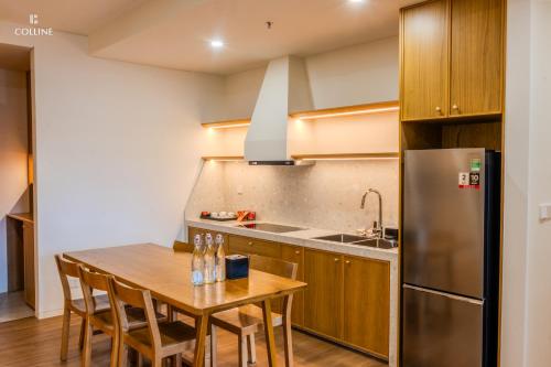 a kitchen with a wooden table and a stainless steel refrigerator at Colline Dalat in Da Lat