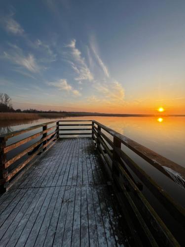 a dock with the sun setting over the water at Widać Wydmy in Łeba