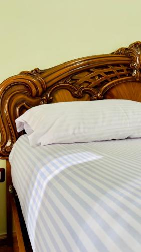 a bed with a wooden head board with white pillows at Berat Central Promenade House in Berat
