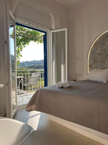 a bedroom with a large bed and a balcony at Andros Tierra Apartments in Batsi