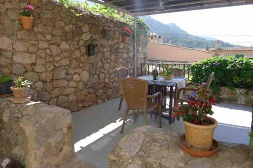 a patio with a table and chairs and a stone wall at Alt Son Lliure beautiful village house in Valldemossa in Valldemossa