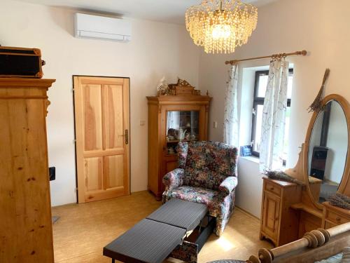 a living room with a chair and a table and a chandelier at Chalupa Na Studené Vodě 