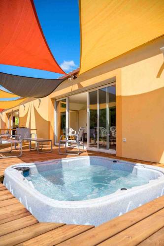 une grande piscine sur une terrasse avec un parasol dans l'établissement Villa Et au milieu coule un ruisseau - Piscine, jacuzzi privé, boulodrome, à Berlou