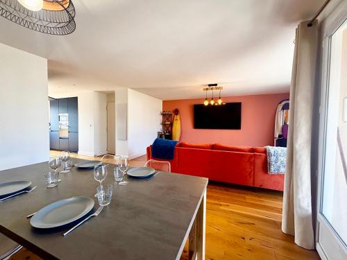 - une salle à manger avec une table et un canapé rouge dans l'établissement Casamea - Spacieux, Moderne, Clim, Parking, à Ajaccio