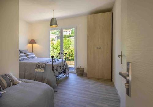 une chambre avec deux lits et une porte avec une fenêtre dans l'établissement Villa Et au milieu coule un ruisseau - Piscine, jacuzzi privé, boulodrome, à Berlou