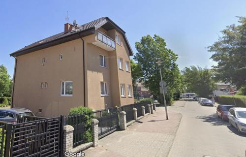 a brown building with a fence next to a street at Pokoje Gościnne u Marcina, Gästezimmer bei Martin in Mielno