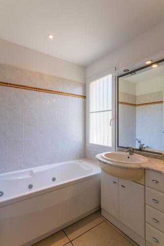 une salle de bain blanche avec une baignoire et un lavabo dans l'établissement Lagrange Vacances - Atlantic Green, à Lacanau-Océan