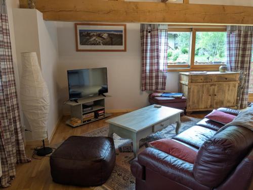 a living room with a couch and a tv at La Grange in Le Noyer