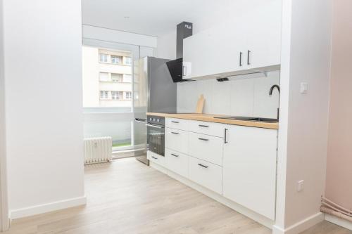Il comprend une cuisine blanche avec des placards blancs et du parquet. dans l'établissement Appartement Messin 3 chambres - Le Terracotta, à Metz