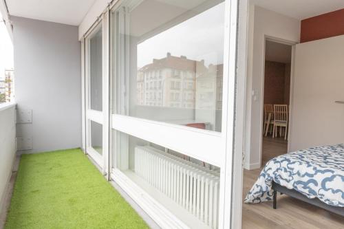 - une chambre avec une grande fenêtre et un tapis vert dans l'établissement Appartement Messin 3 chambres - Le Terracotta, à Metz