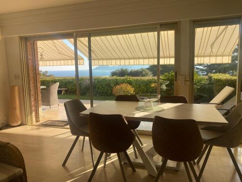 une salle à manger avec une table et des chaises et une grande fenêtre dans l'établissement Appartement - villa Le Saint Georges avec superbe jardin et vue mer panoramique, à Cannes