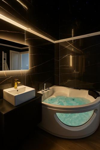 une salle de bain avec une baignoire et un lavabo dans l'établissement Nuit Dans les Étoiles - Spa Balnéo & Sauna Privé, à Troyes