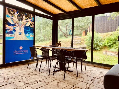 a table and chairs in a room with a large window at Camping centra Shambhala in Lúčka