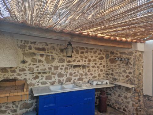 a kitchen with a blue sink and a stone wall at Lesvos Traditional Preserved House in Vasiliká