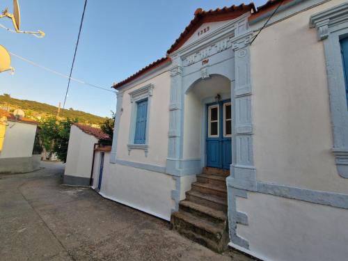 a white house with a blue door and stairs at Lesvos Traditional Preserved House in Vasiliká