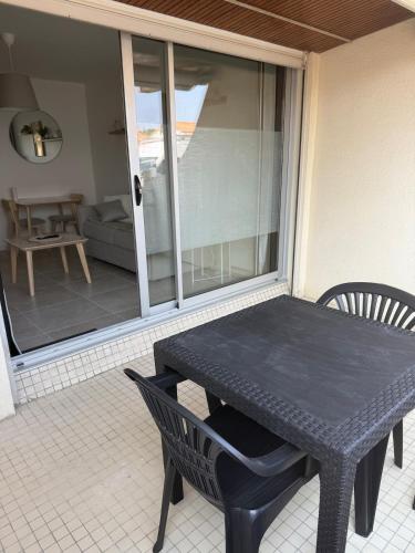 - une table et des chaises noires sur une terrasse couverte dans l'établissement La parenthèse - 50 m de la plage, à Saint-Hilaire-de-Riez
