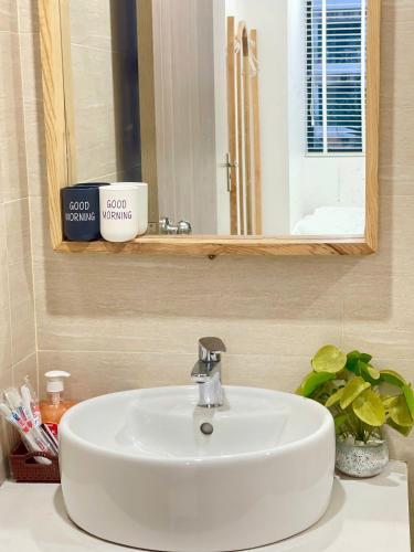 a white sink in a bathroom with a mirror at Châu Giang Homestay, Nera Garden Huế in Thôn Văn Dương