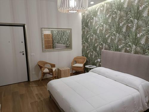 a bedroom with a bed and two chairs and a painting at PIANESE house 1 in Campobasso